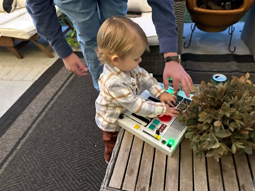 A toddler jamming on The Beat Brick with an adult nearby