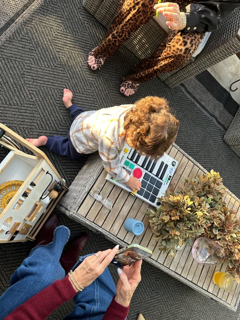 A toddler playing The Beat Brick on a patio table